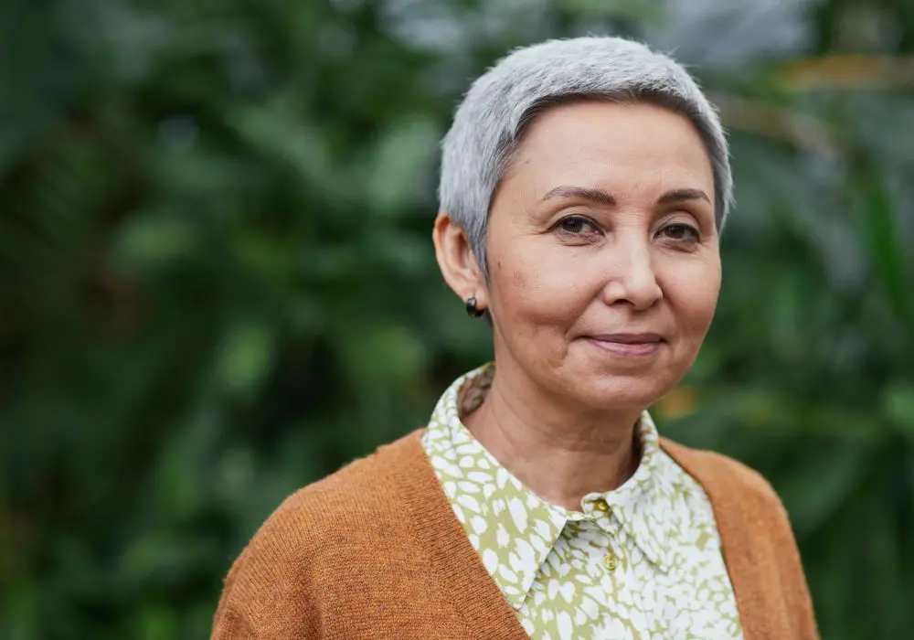 A woman with grey hair wearing an orange sweater.